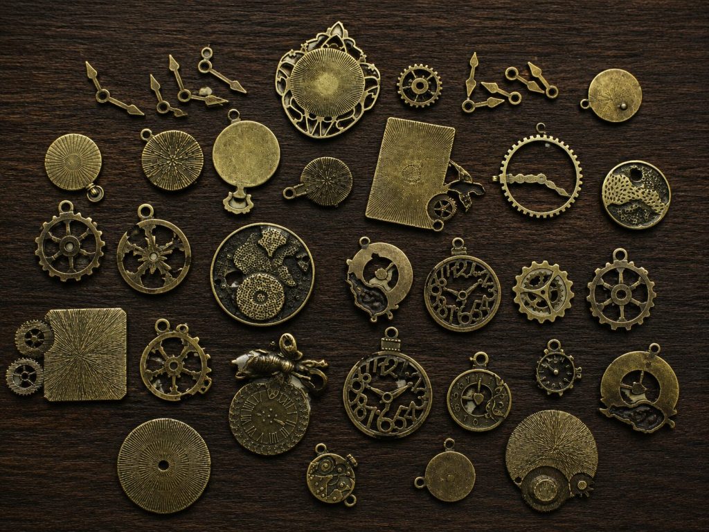 Gear charms spread across dark velvet or wood - variety of sizes and shapes showing the 30-piece mix
